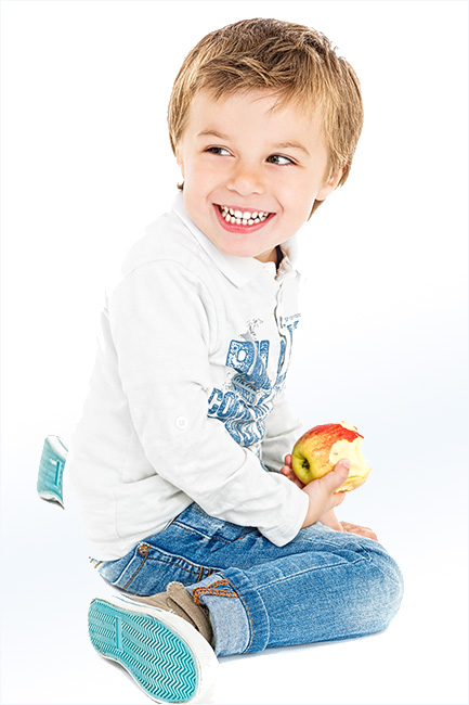 Kleiner Junge sitzt auf dem Boden - ©kreativloft.ch, stock.adobe.com nge mit Jeans und Pullover sitzt auf dem Boden hält einen angebissenen Apfel in der Hand. Er schaut nach hinten und lacht.
